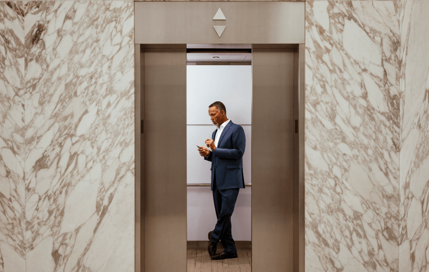 Мъж, използващ телефона си в асансьор