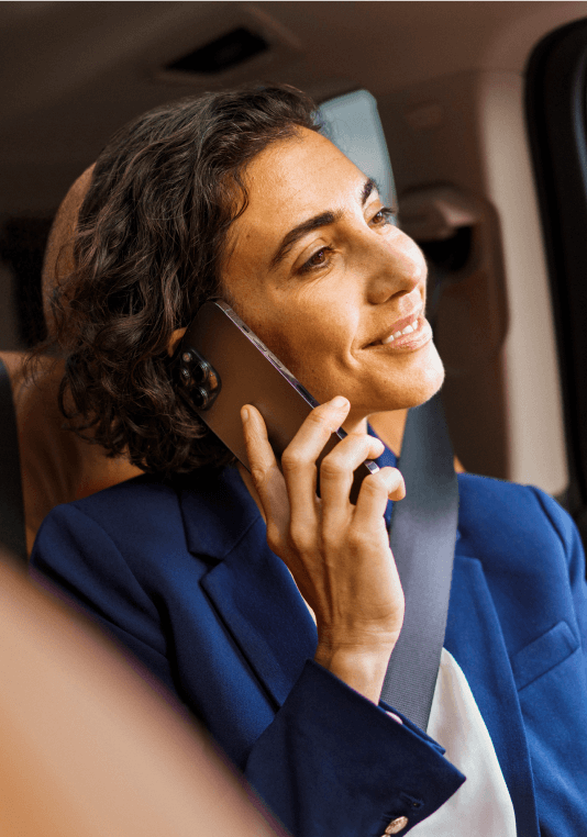 Клиентка се усмихва, докато държи мобилния си телефон в кола