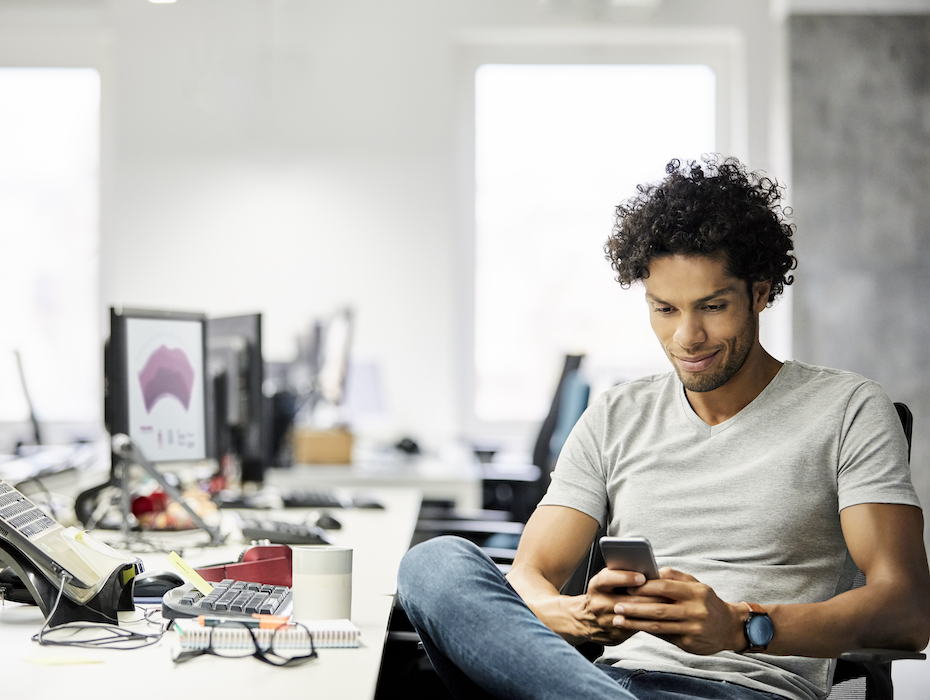 Male entrepreneur SMS messaging while sitting at desk