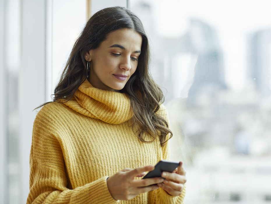 Confident businesswoman using mobile phone for business SMS messages.
