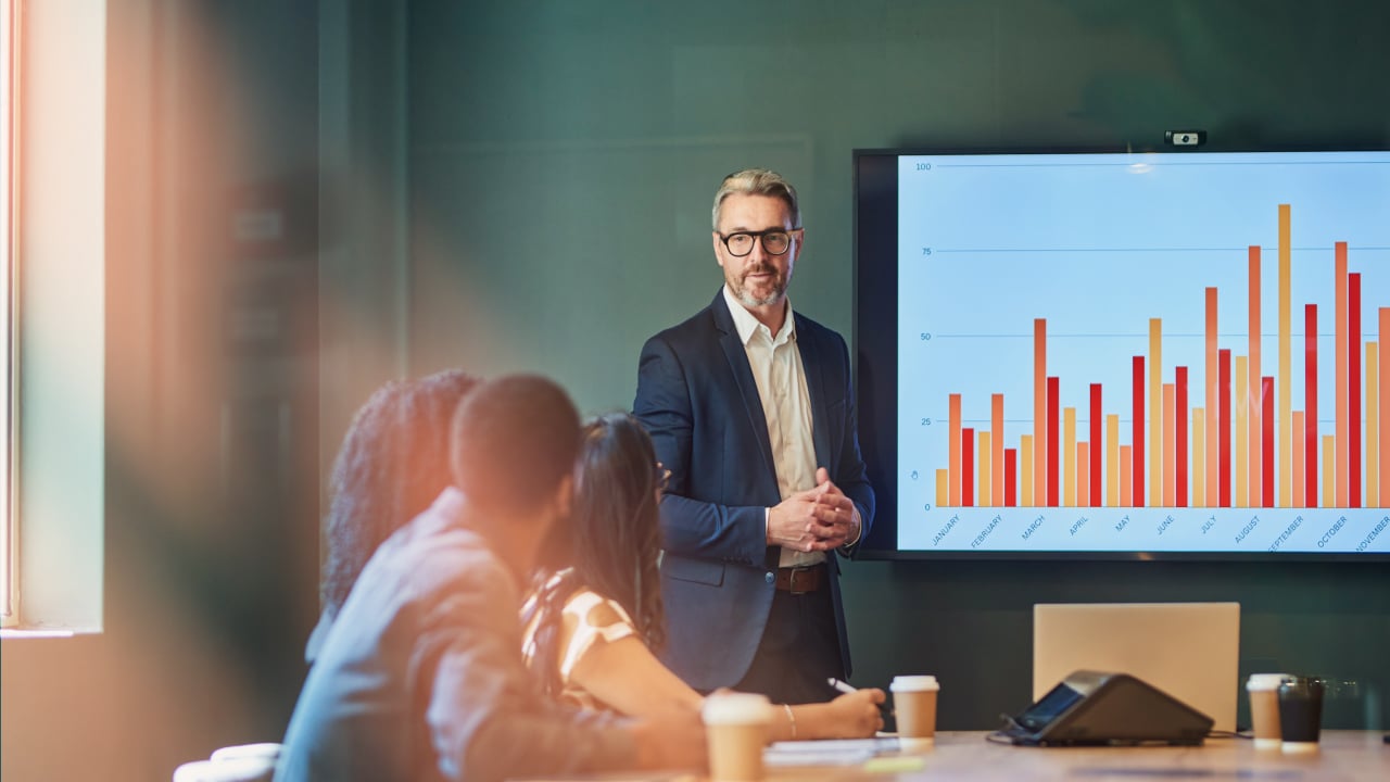 Wealth management man in front of graph in conference room