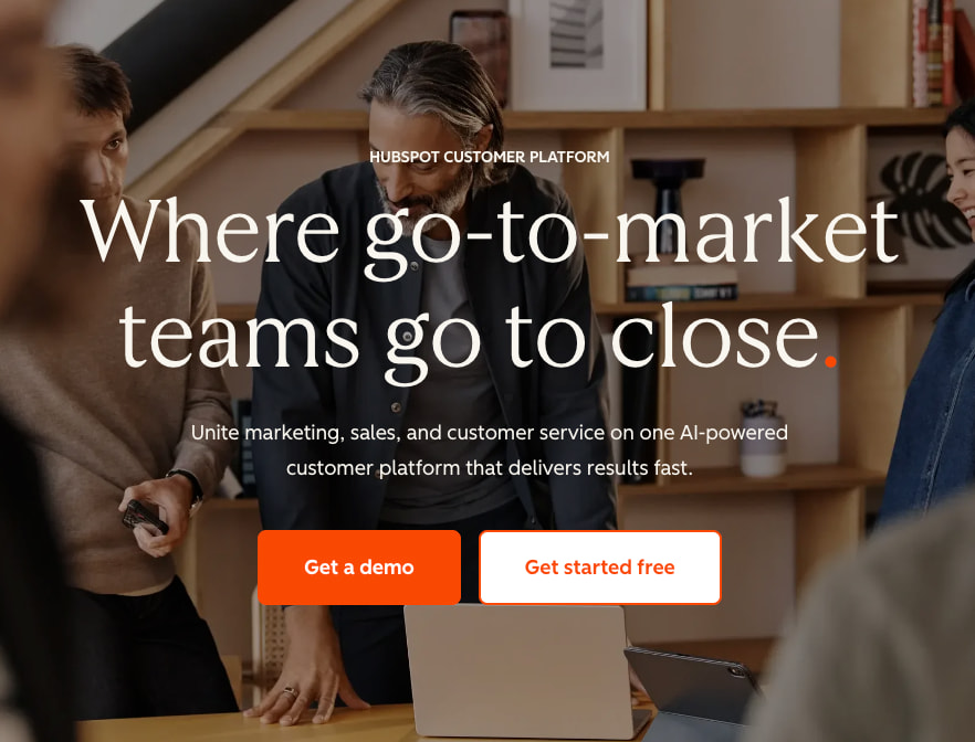 A group of coworkers talking with an overlay of the tagline 'Where GTM teams go to close' plus demo and get started buttons